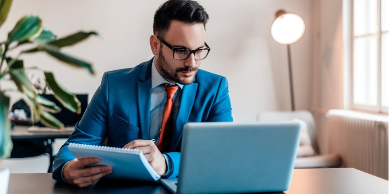 attractive-man-working-in-office-taking-notes-while-looking-at-laptop-picture-id920403370 (2)