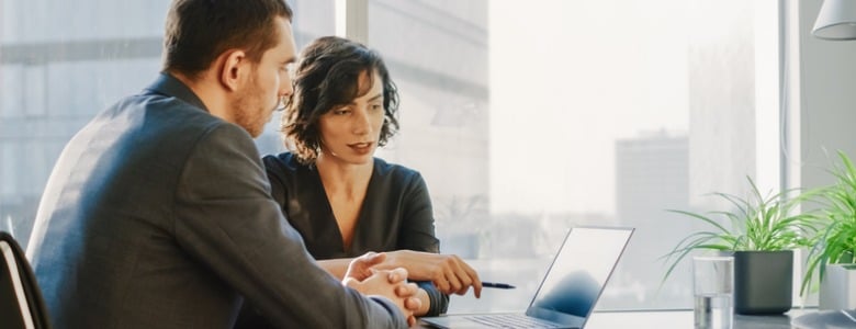man and woman in an office building looking at a laptop